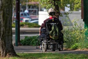 Guy sitting on a motorized wheelchair going through a park